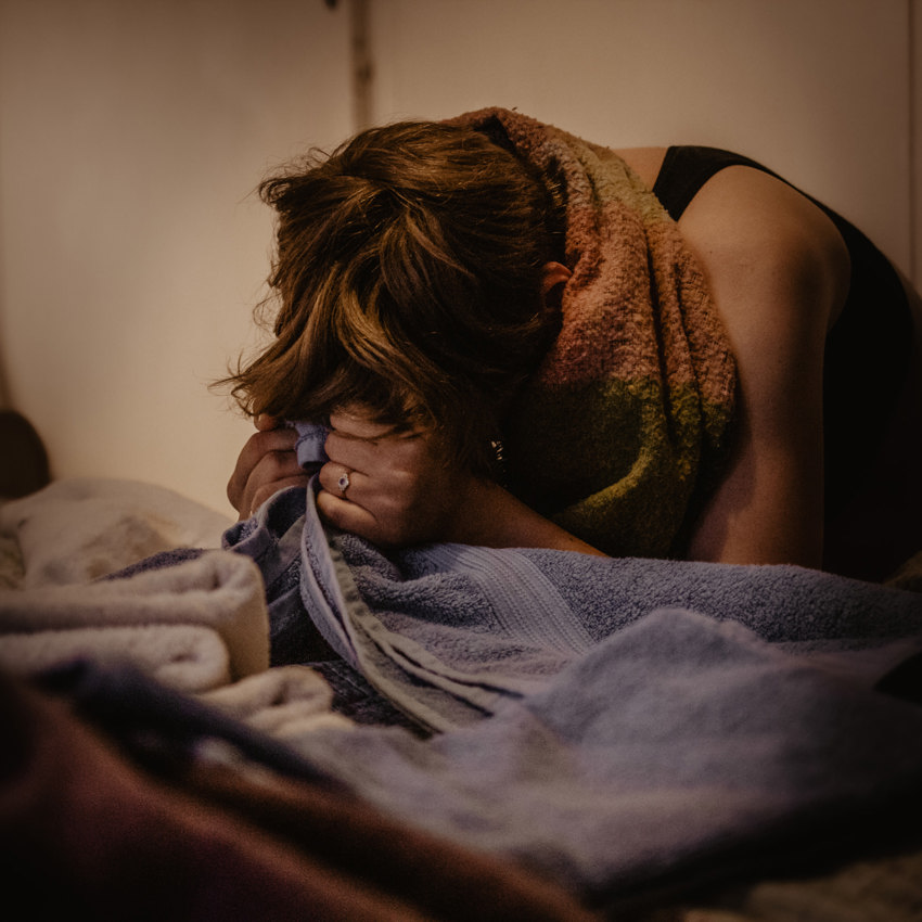 Woman giving birth leaning over a bed